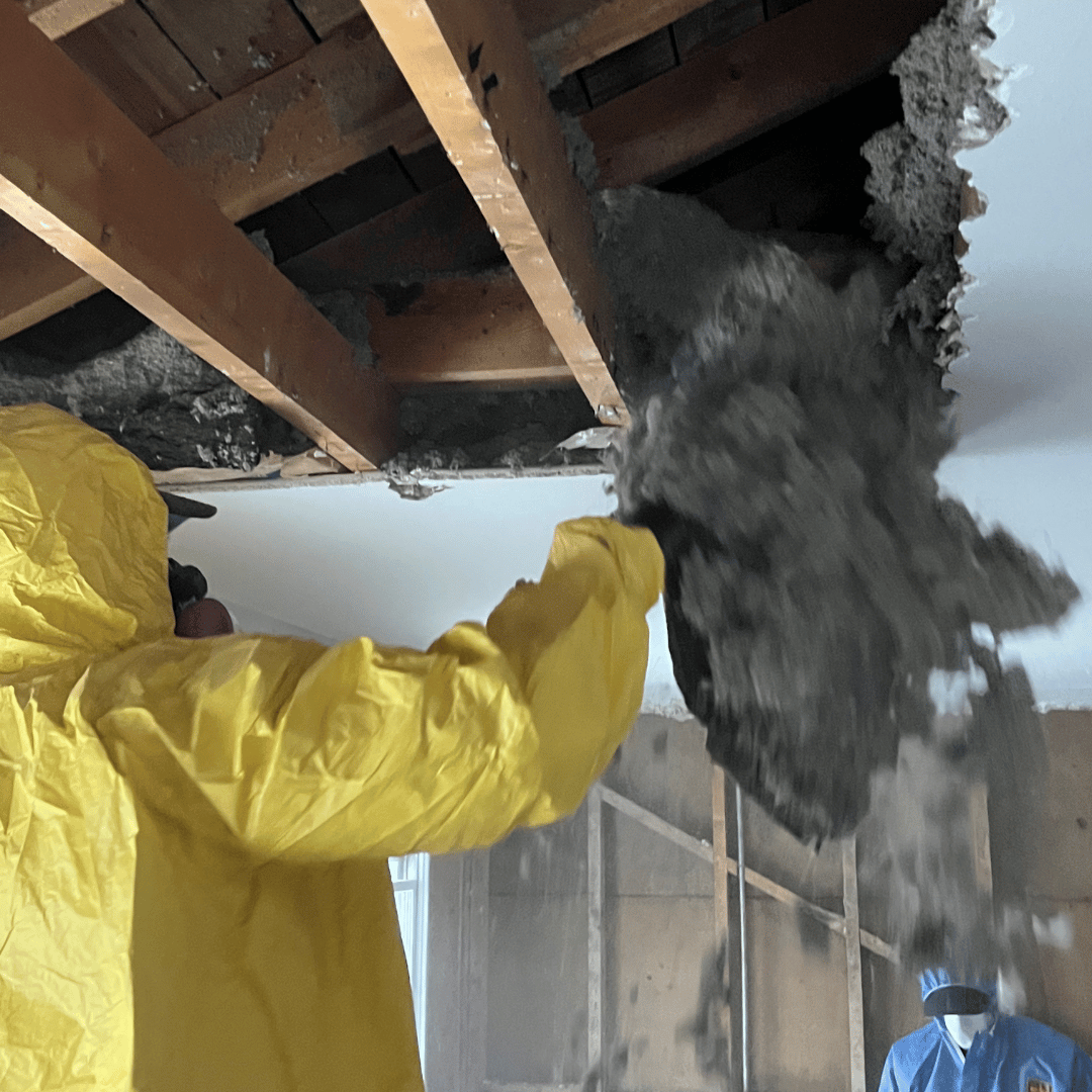 Person in yellow hazmat suit removing insulation from ceiling - HRS Restoration Services in Aurora, CO.
