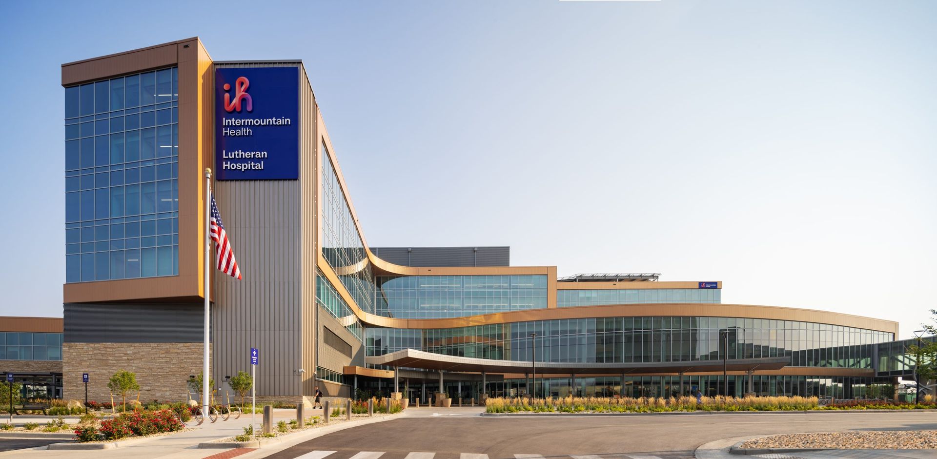Modern hospital building with a large blue sign and American flag.
