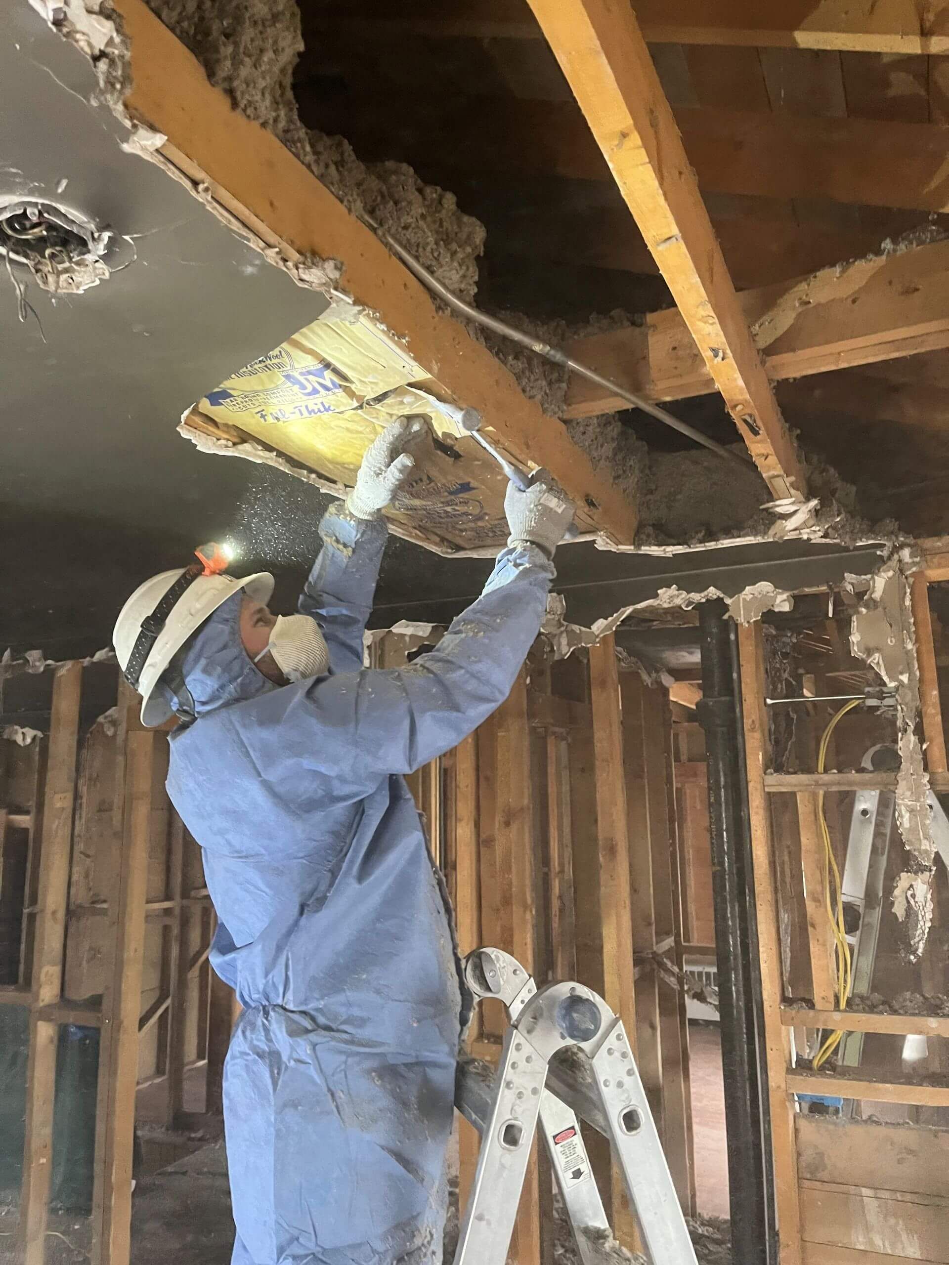 HRS Restoration Services worker in protective gear restoring damaged wall in a Denver Colorado home