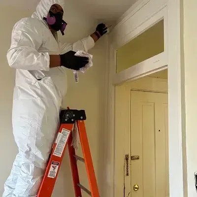 HRS Restoration Services technician in protective suit performing mold remediation on interior wall in Denver Colorado