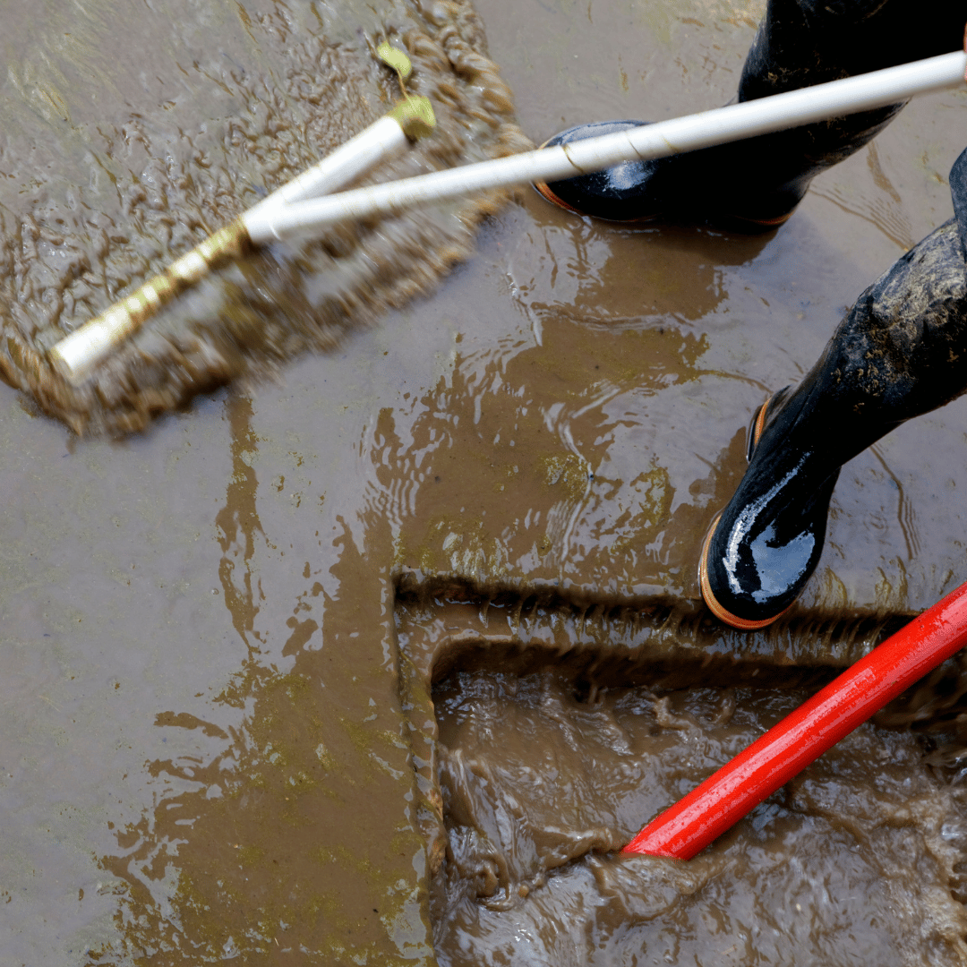 Emergency sewage cleanup in Denver, CO — HRS technician removing contaminated water with industrial broom.