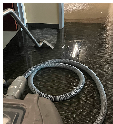Vacuum cleaner on a wet, dark floor near a doorway. The hose is coiled on the floor.