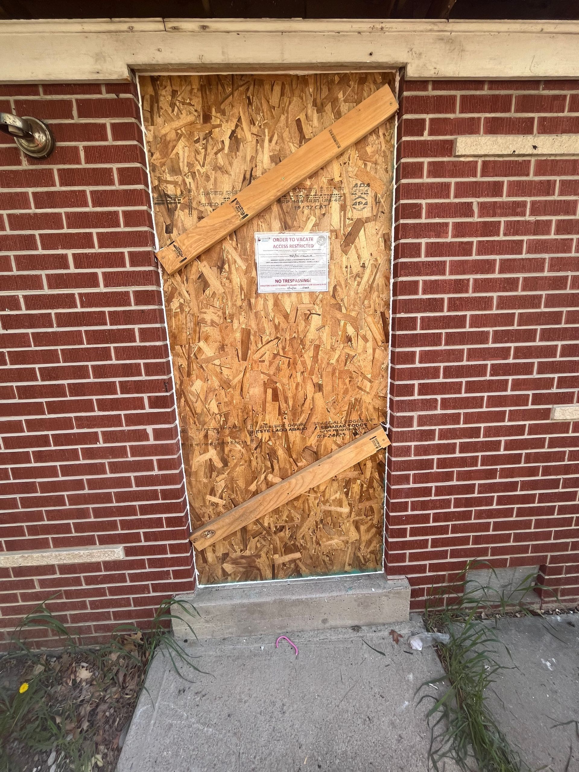Boarded doorway with bracing to help prevent unauthorized entry and protect a damaged building.
