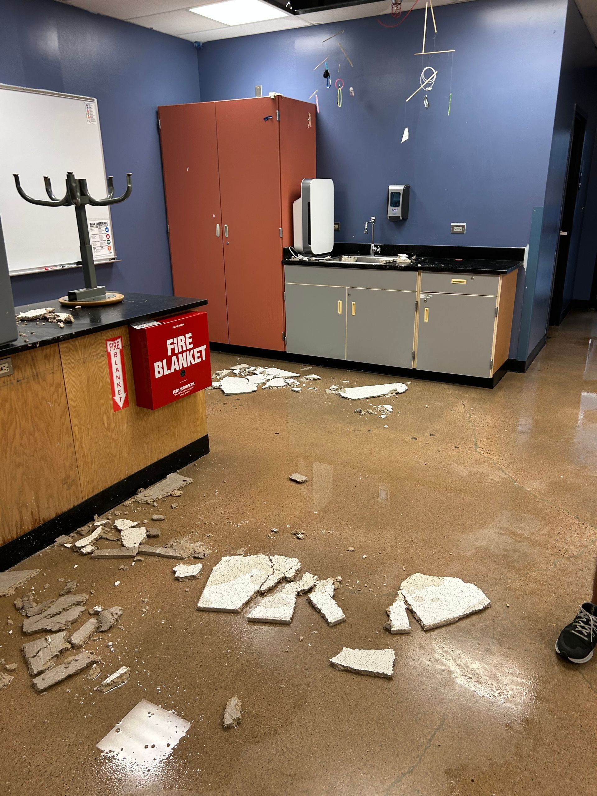Water damage restoration in a Denver classroom after ceiling collapse. HRS technicians prepare for structural drying.