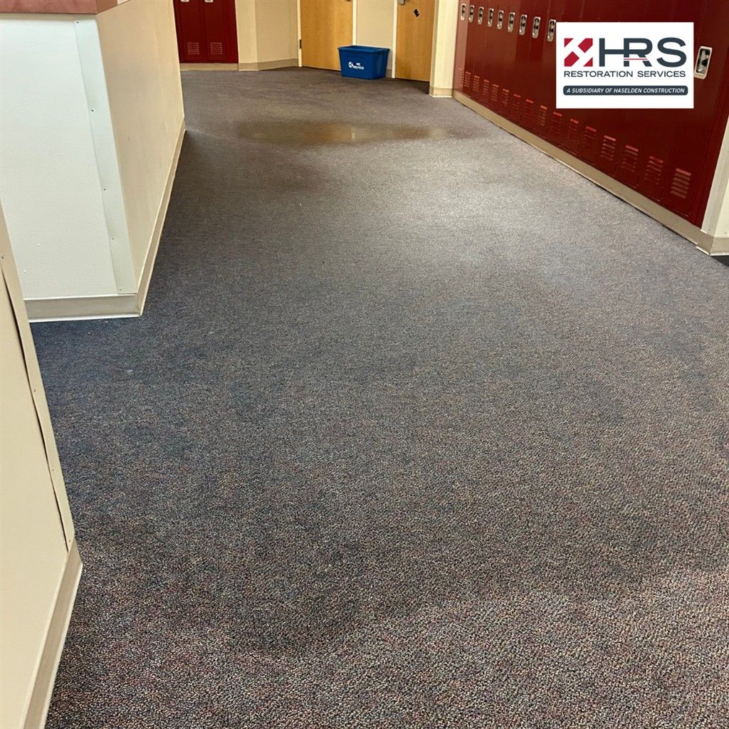 Water damage affecting a school hallway floor during restoration work in Meridian, CO