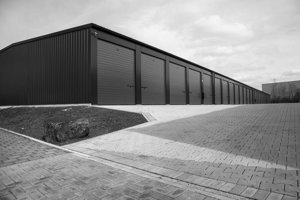 A Row of Storage Units with Red Doors in A Parking Lot — ShedPro Constructions in Darawank, NSW
