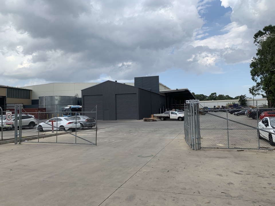 A Large Warehouse with A Lot of Cars Parked in Front of It — ShedPro Constructions in Darawank, NSW