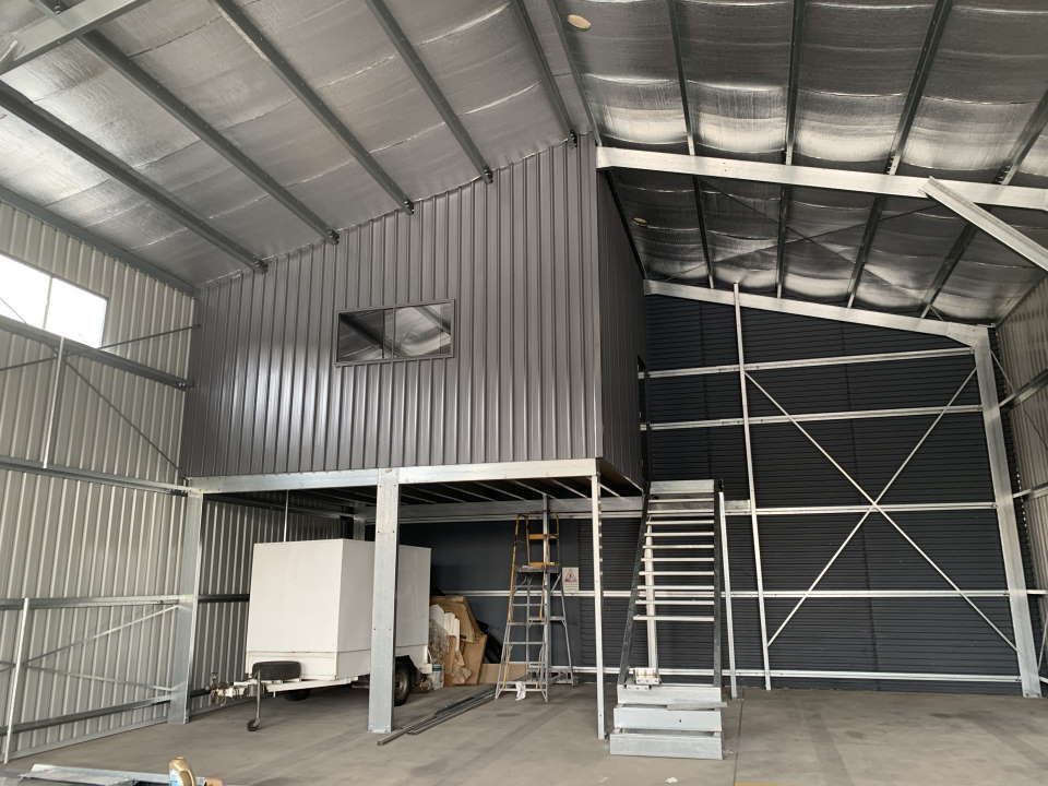A large warehouse with a trailer parked underneath it — ShedPro Constructions in Darawank, NSW
