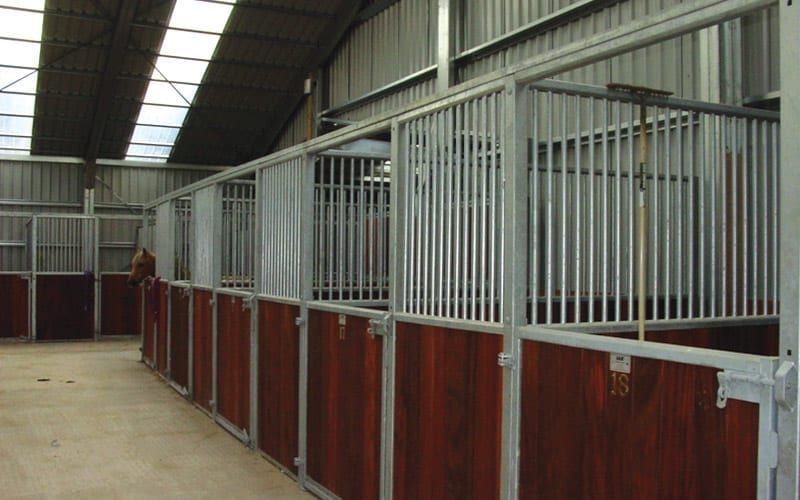 A Row of Stables with Wooden Doors and Metal Bars — ShedPro Constructions in Darawank, NSW