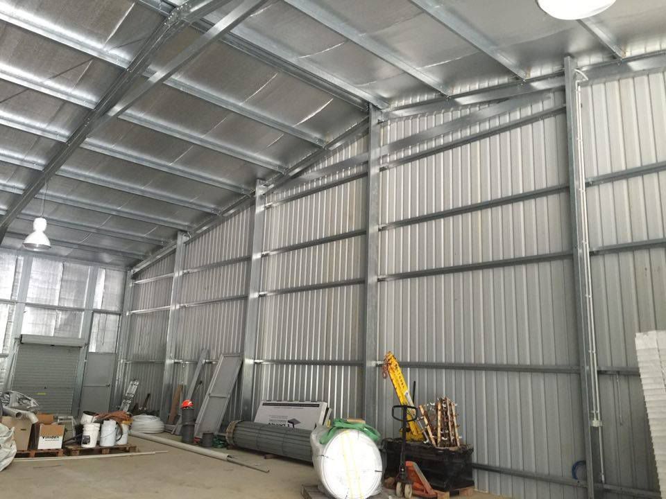 A Large Warehouse with A Metal Roof and A Lot of Boxes on The Floor — ShedPro Constructions in Darawank, NSW
