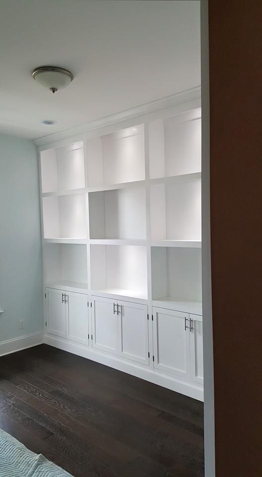 a room with a lot of white shelves and cabinets