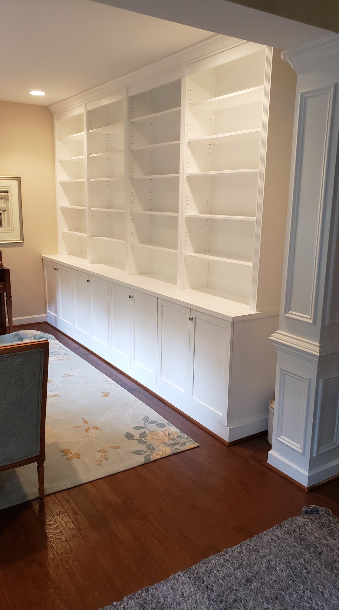 a living room with white shelves and a rug