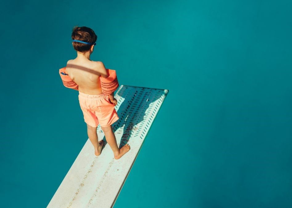 child on a diving board above a swimming pool