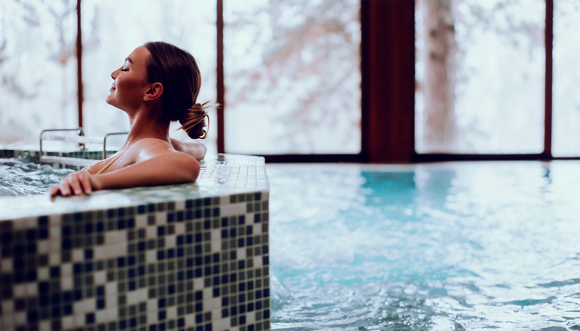 woman relaxing in a jacuzzi flowing into a swimming pool