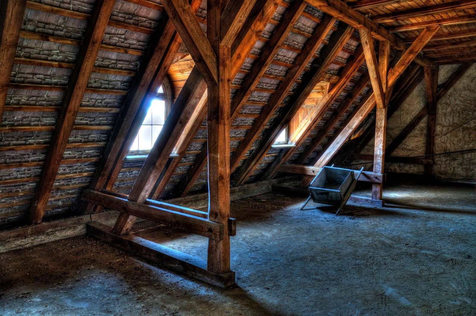 An empty attic with wooden beams and a chair.