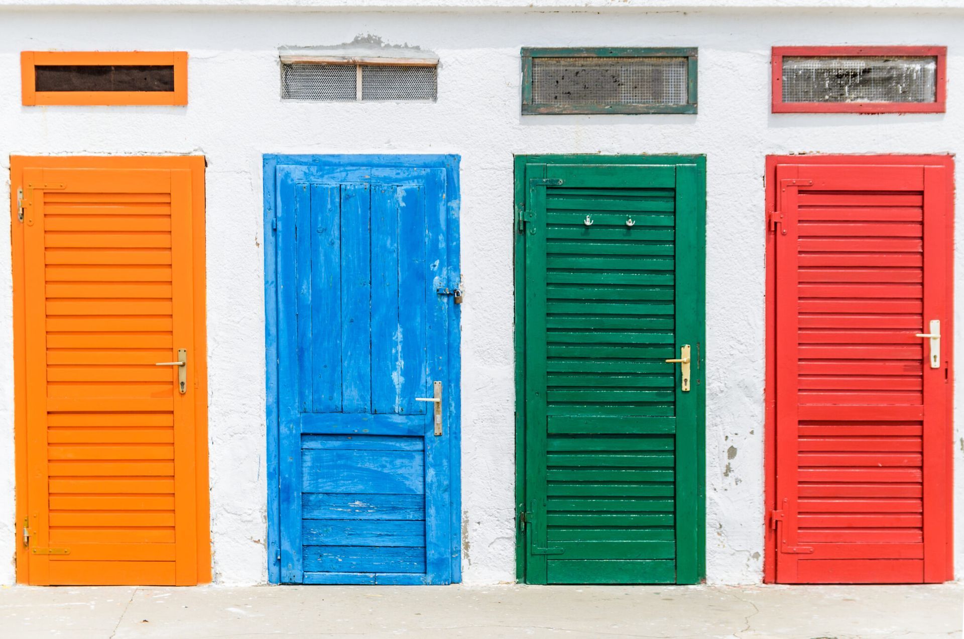 A row of colorful doors on a white wall