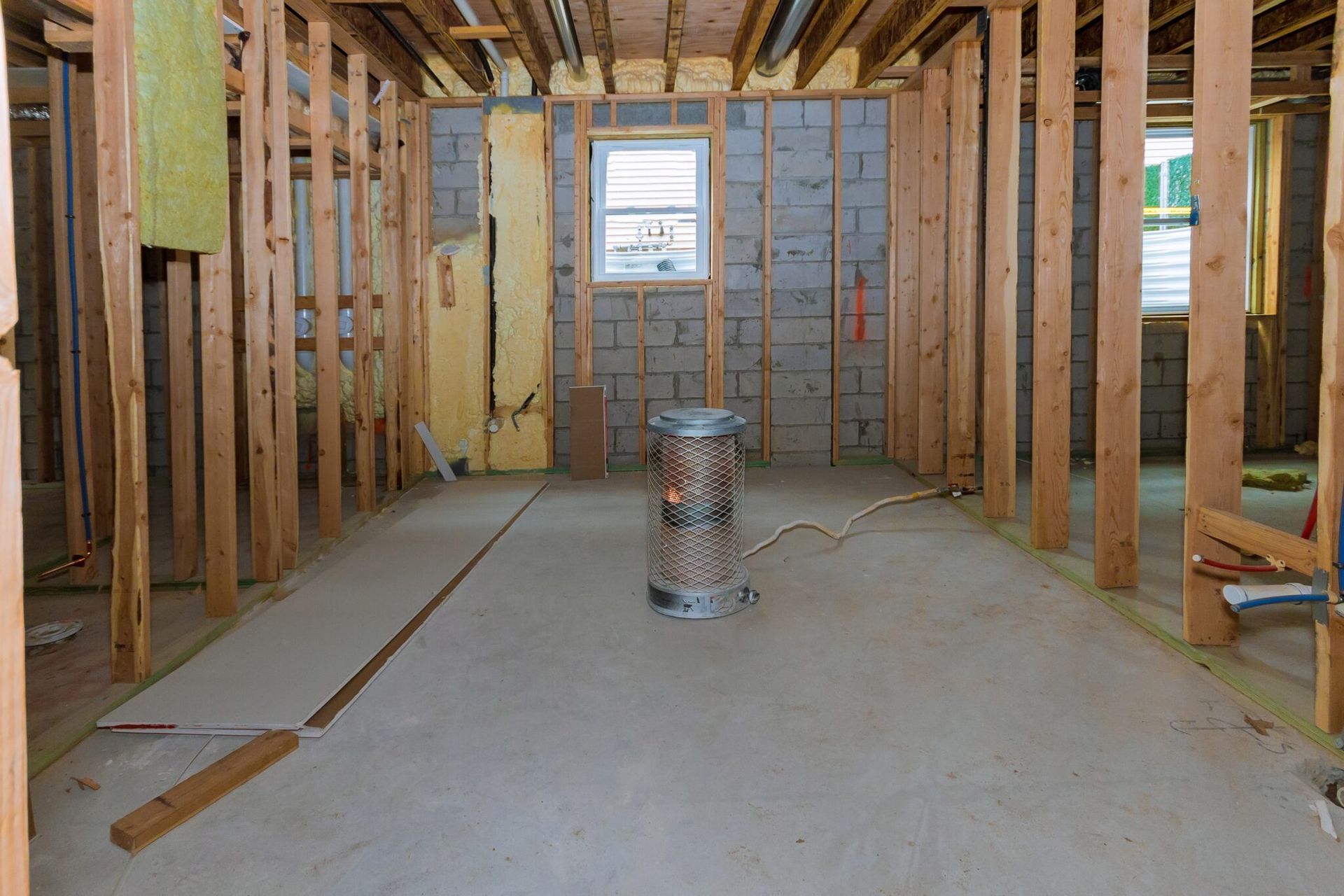 A room in a house under construction with wooden beams and a window.