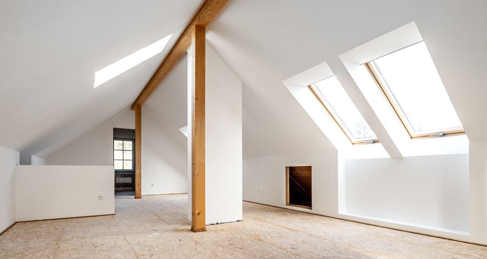 An empty attic with two skylights and wooden beams