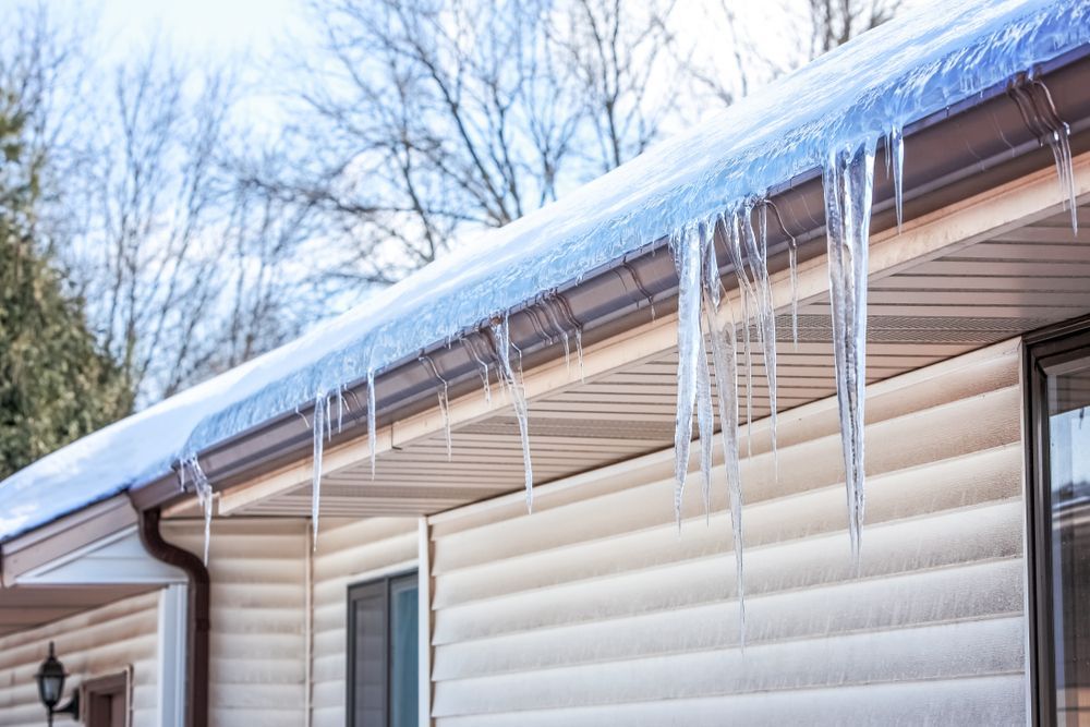 Icicles are hanging from the roof of a house.