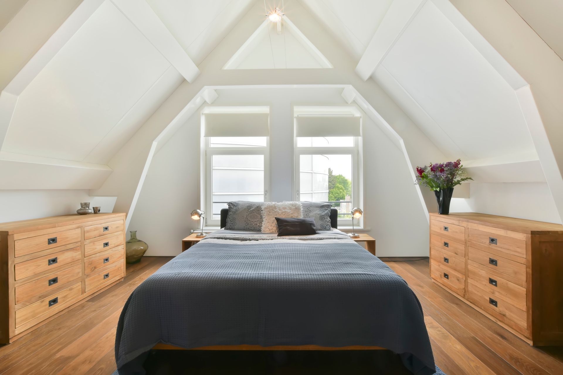 A bedroom with a bed , dresser , and two windows.