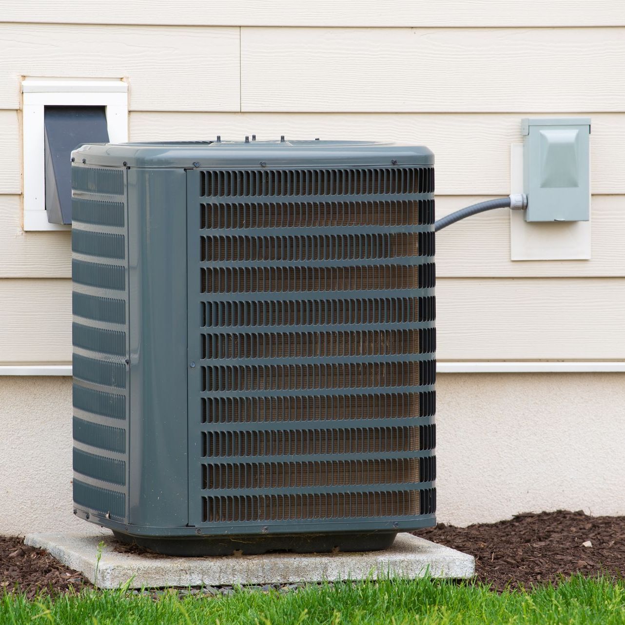 An air conditioner is sitting on the side of a house.