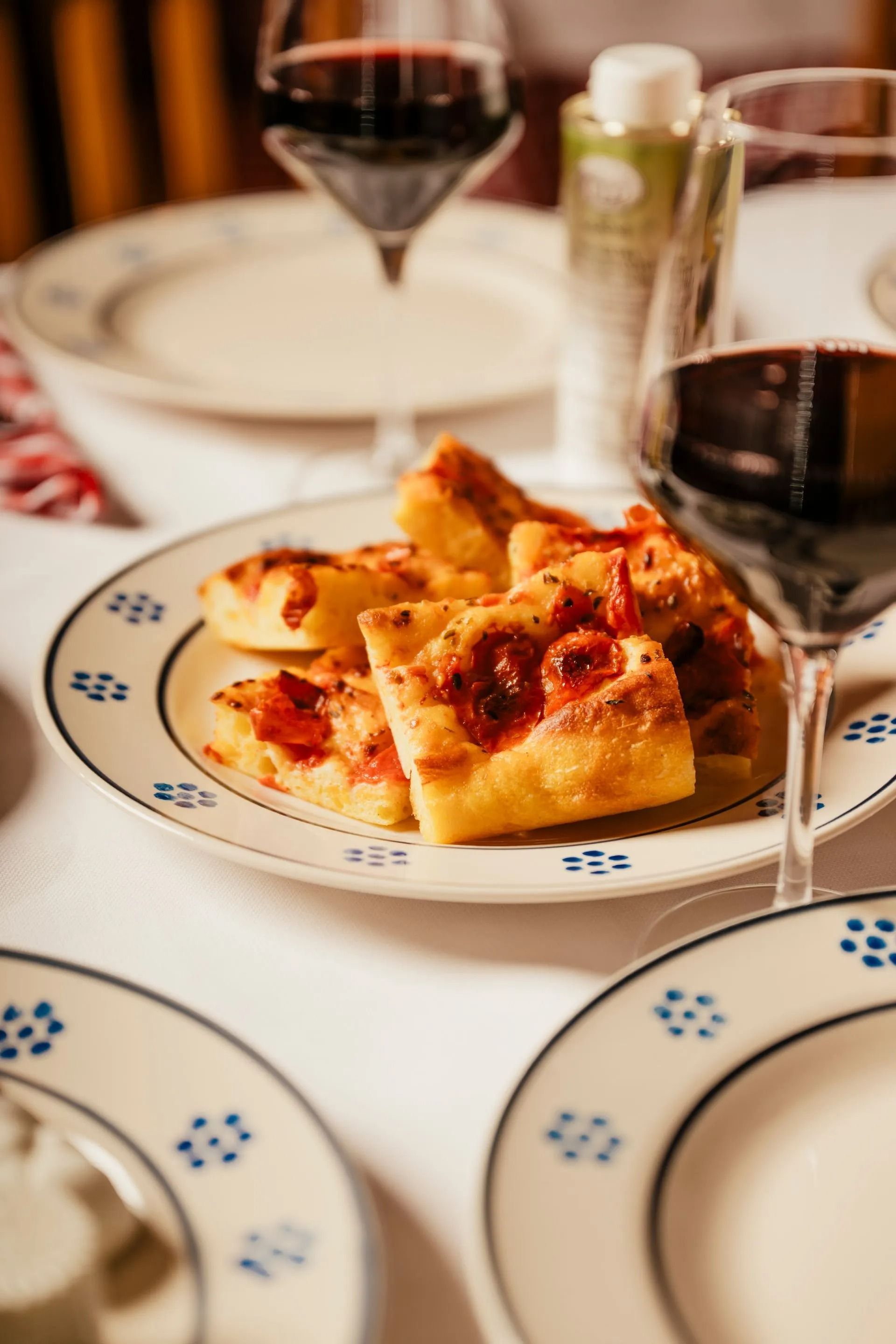 Wine glasses and plates of sliced pizza on a set dining table