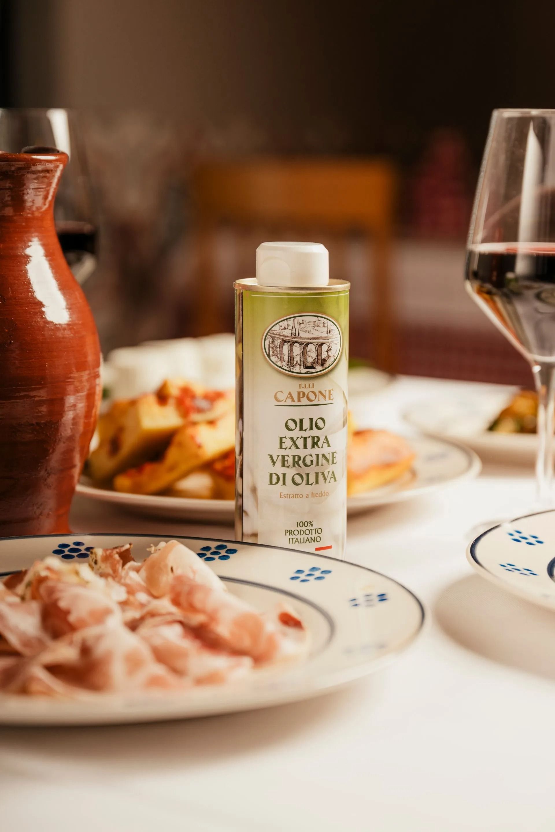 Dining table with wine glass, dishes, and a small bottle of olive oil in the center
