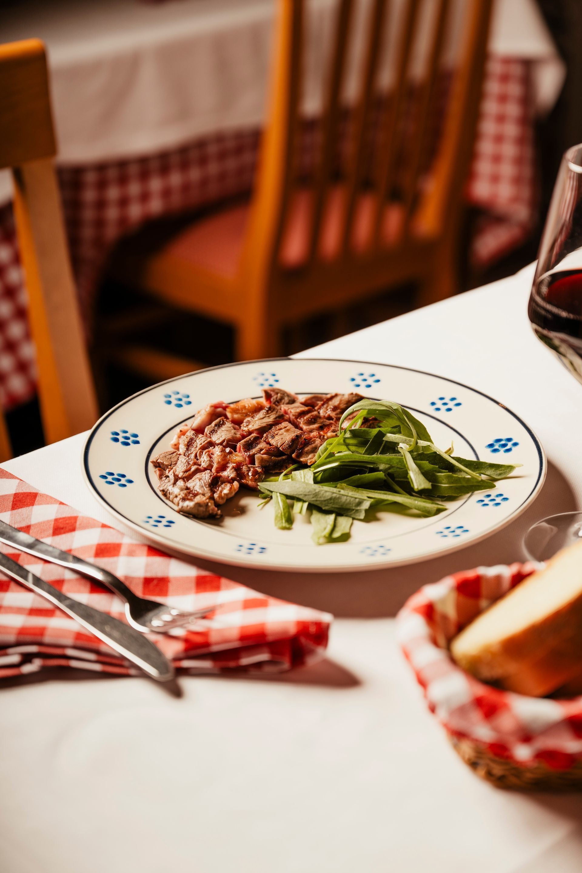 Plated steak and green beans on a checkered tablecloth in a cozy restaurant setting