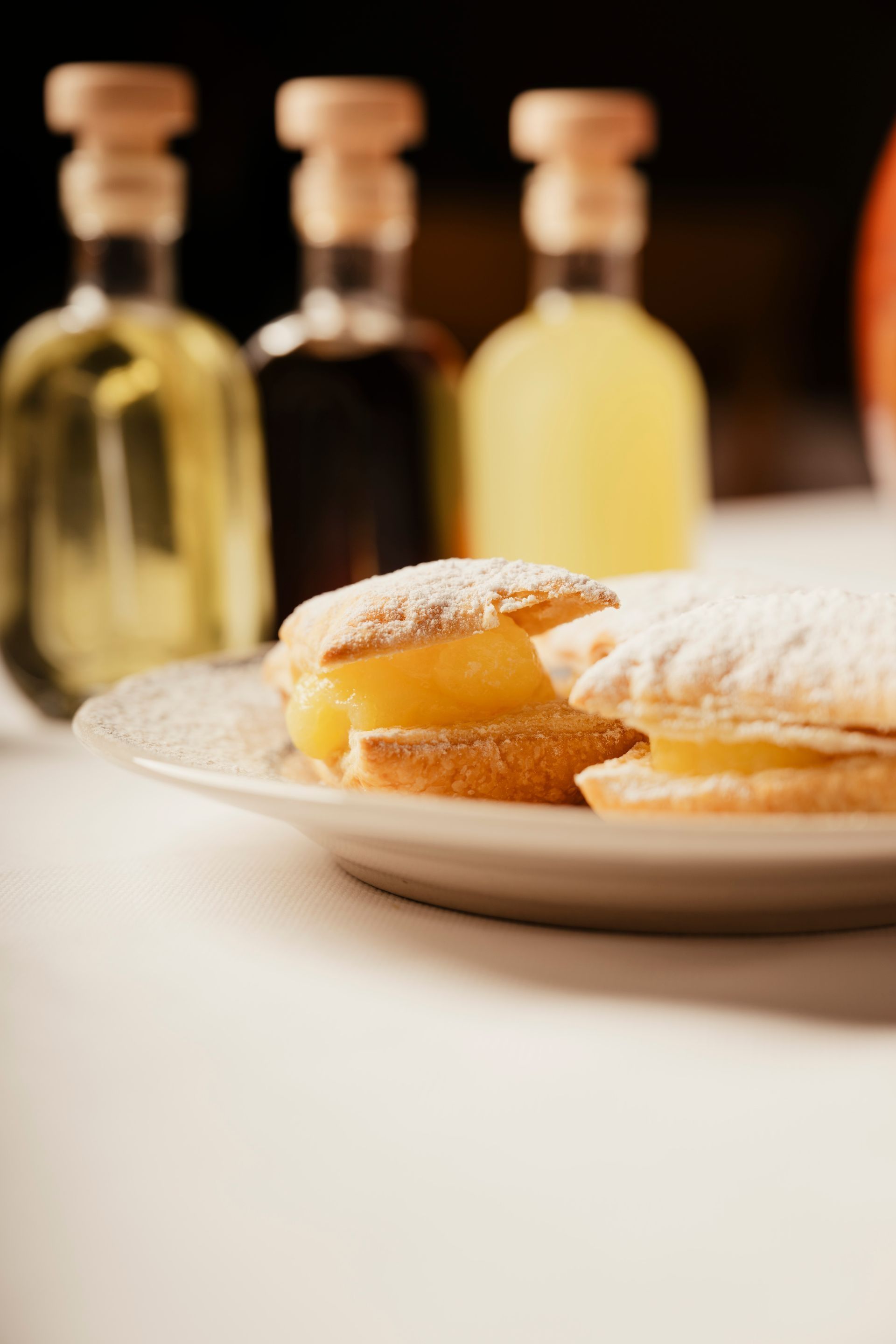 Powdered sugar pastries on a plate with bottles blurred in the background