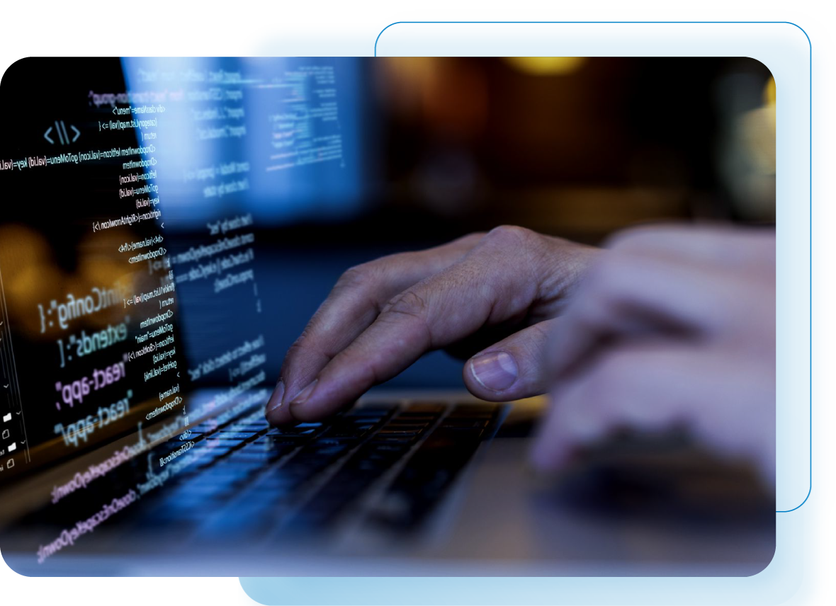 Mãos de uma pessoa digitando em um laptop com linhas de código exibidas na tela. O ambiente é escuro com iluminação azul.
