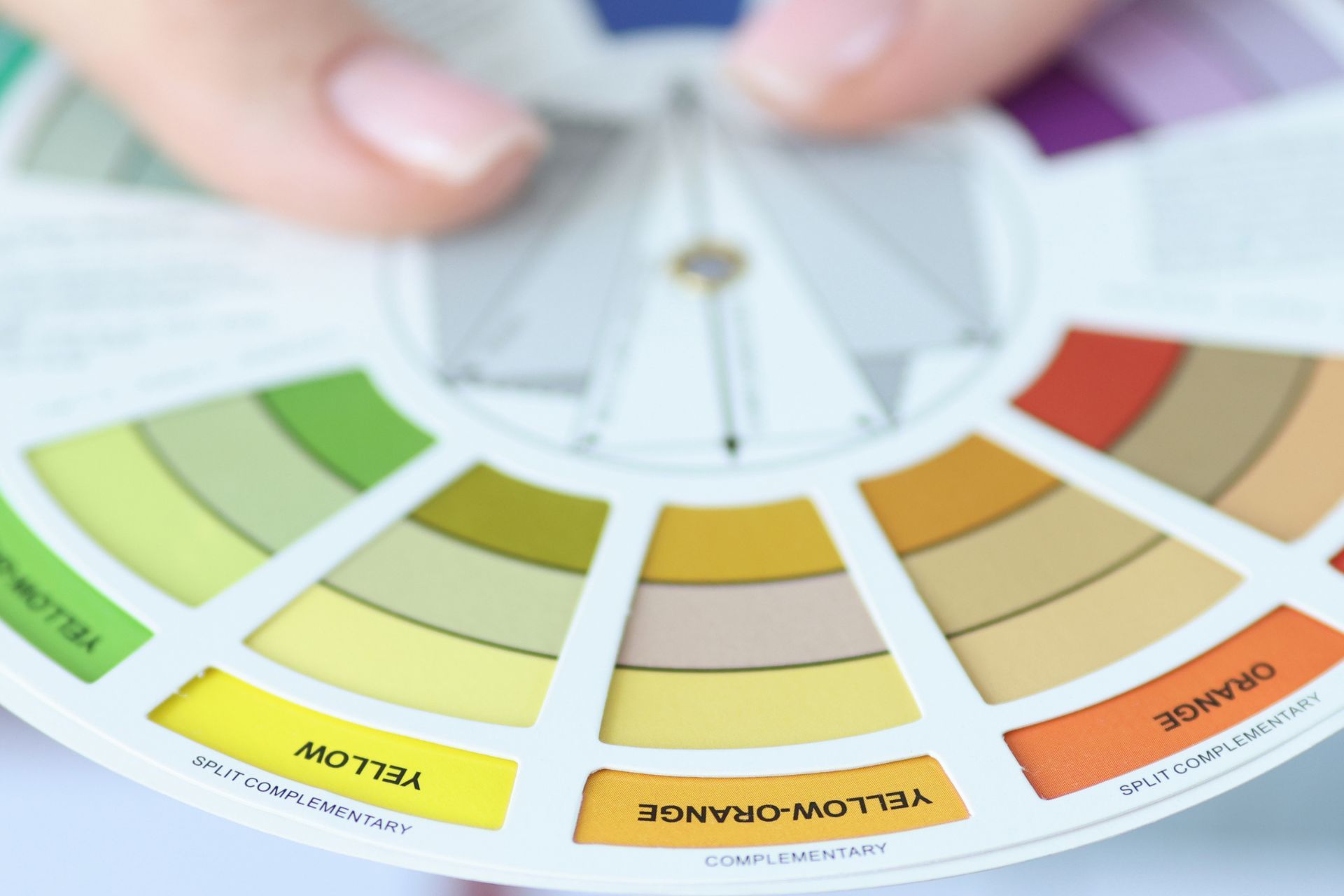 Close-up of a hand holding a color wheel guide for interior design.