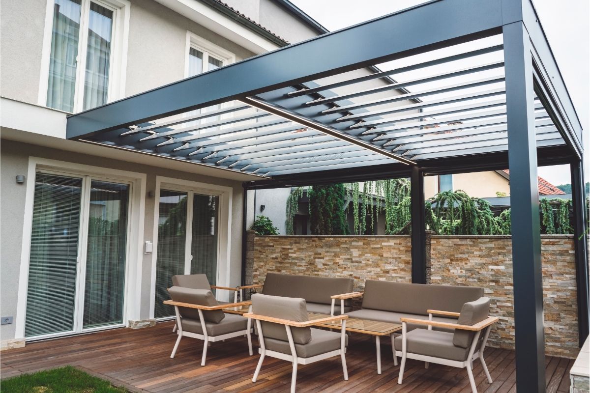 Modern pergola over a chic patio set against a home and greenery in Henderson, creating a cozy nook.