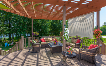 A photo of a pergola built into a deck in the backyard oasis of a house in Henderson, Nevada. The deck has 2 levels. An upper level that connects to the house and a lower level that meets the yard.