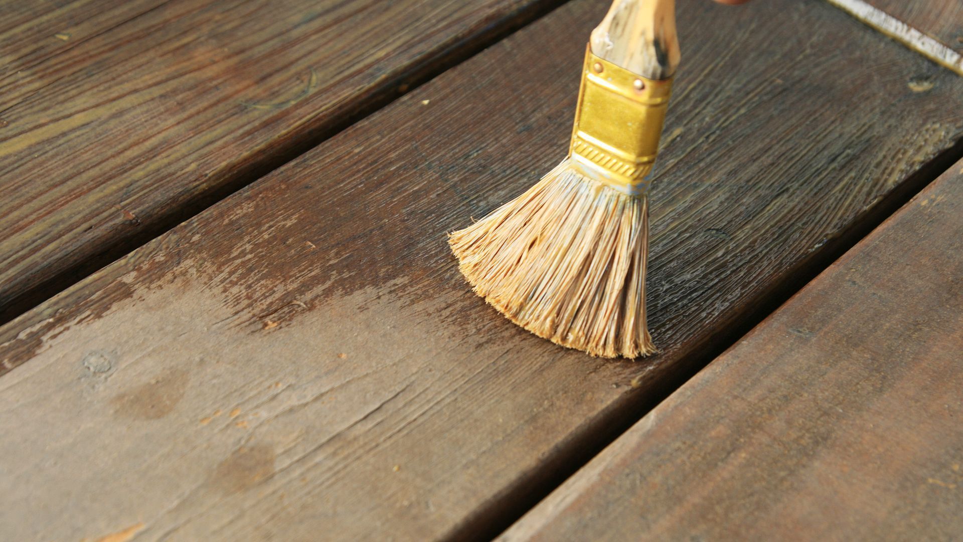 Close-up of a brush waterproofing a wooden deck in Henderson, NV, showing detailed strokes.