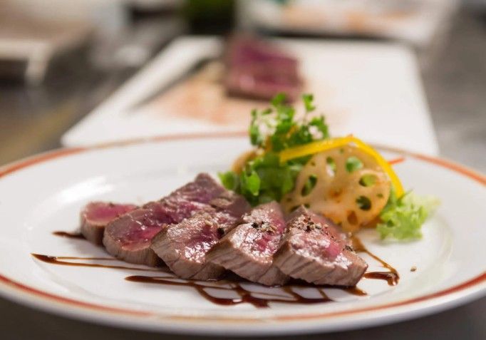 Un piatto bianco con carne e verdure su un tavolo