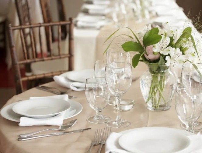 Un tavolo con piatti, bicchieri e un vaso di fiori.