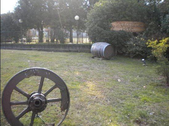 Una ruota di carro è seduta nell'erba accanto a un barile