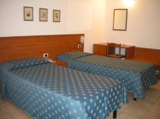 Una camera d'albergo con due letti e una scrivania