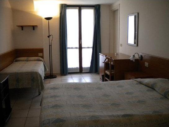 Una camera d'albergo con due letti e una scrivania