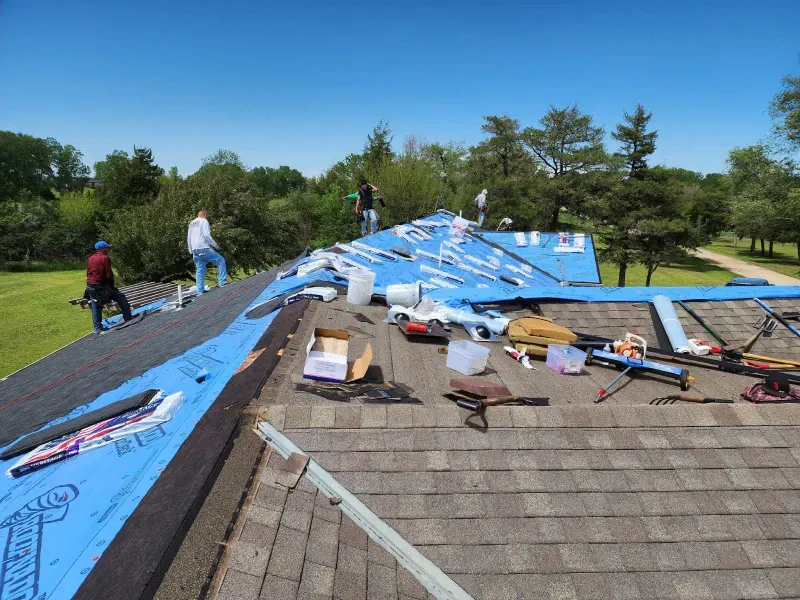 A group of people are working on the roof of a house.