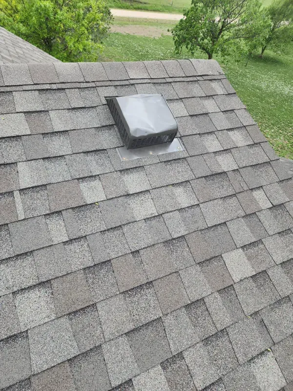 A roof with shingles and a skylight on top of it.