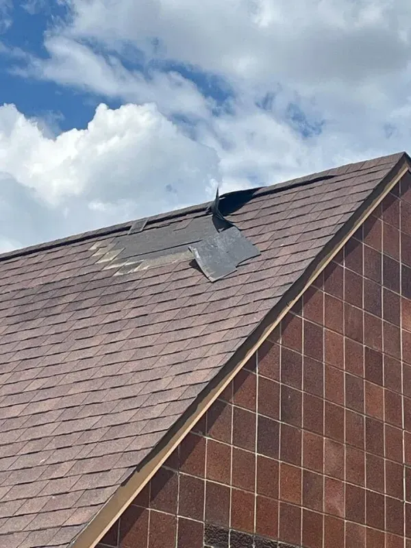 A roof with a hole in it and a blue sky in the background.