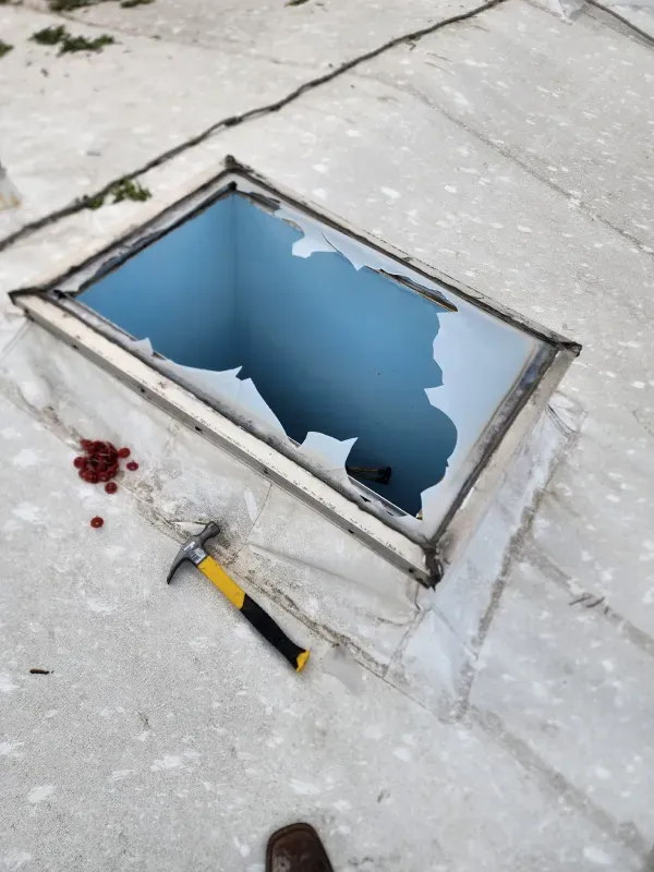 A skylight with a hole in it and a hammer next to it