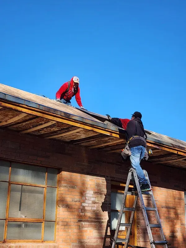 Two men are working on the roof of a building.