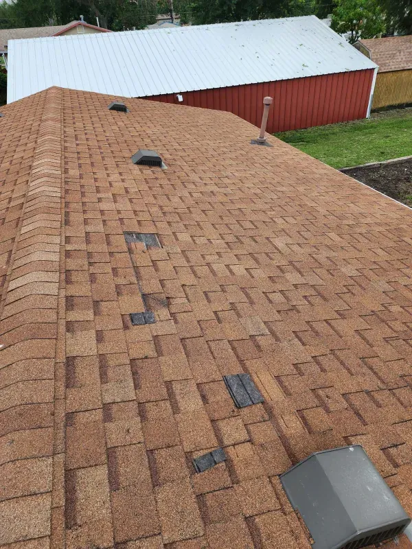 The roof of a house with a red barn in the background.