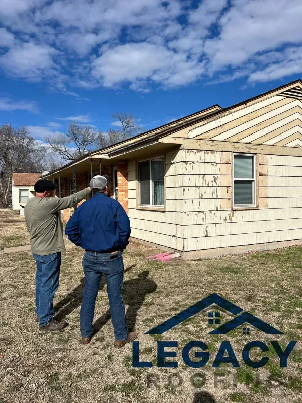 Two men are standing in front of a house looking at it.