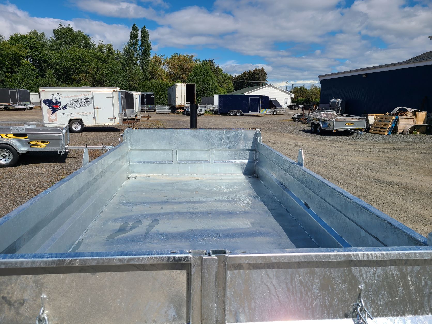 Une remorque est garée sur un parking à côté d'un bâtiment.