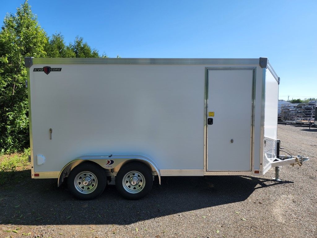Remorque cargo blanche fermée à deux roues, avec porte et attelage, sur fond de ciel bleu.
