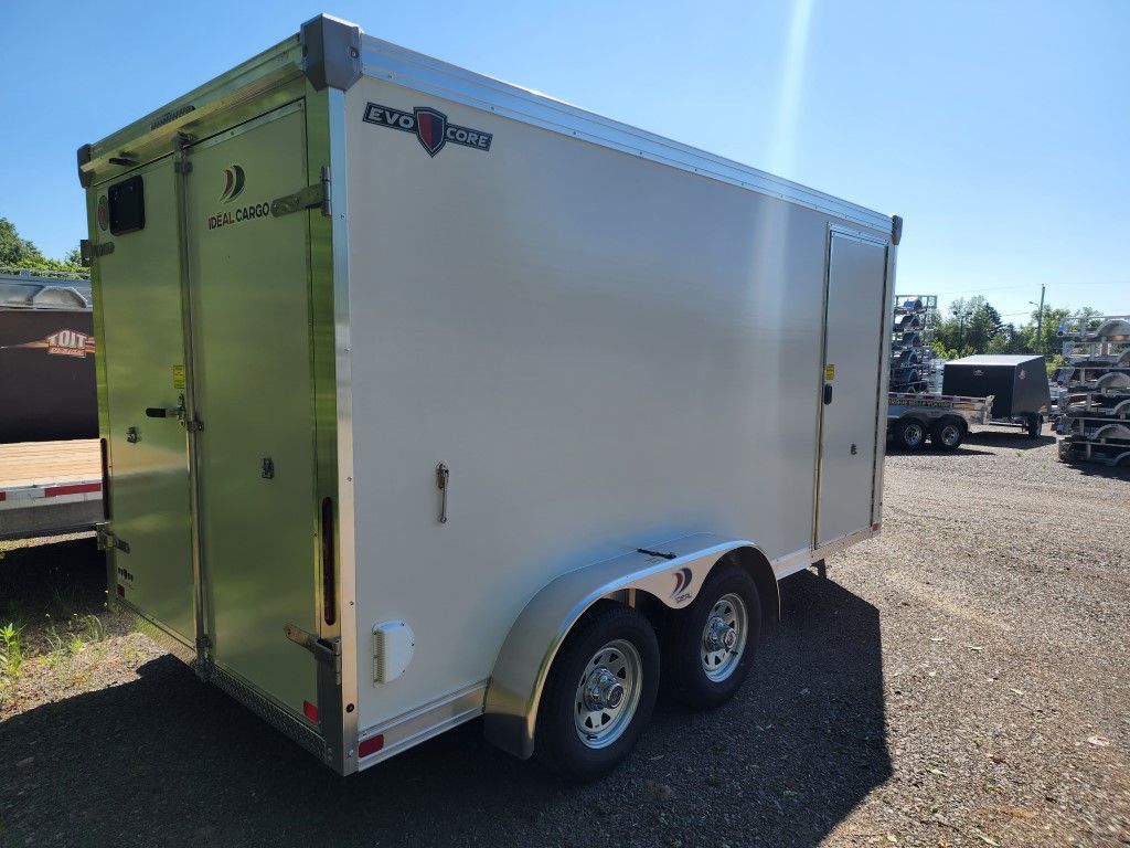 Remorque cargo fermée, beige avec garnitures argentées, sur un terrain extérieur.