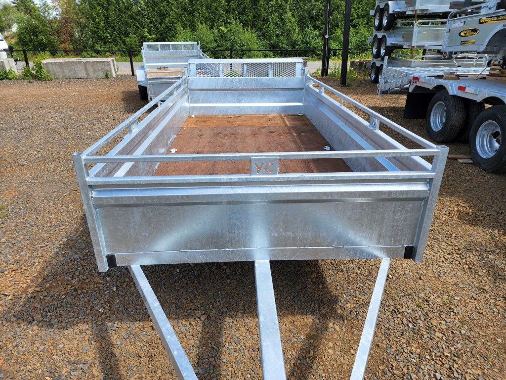 Une remorque en métal est garée sur un terrain en gravier.